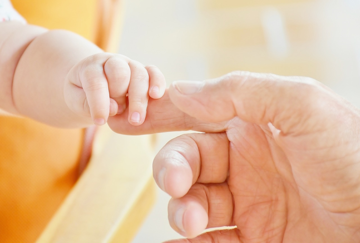 A picture of a baby's hand holding their parent's finger